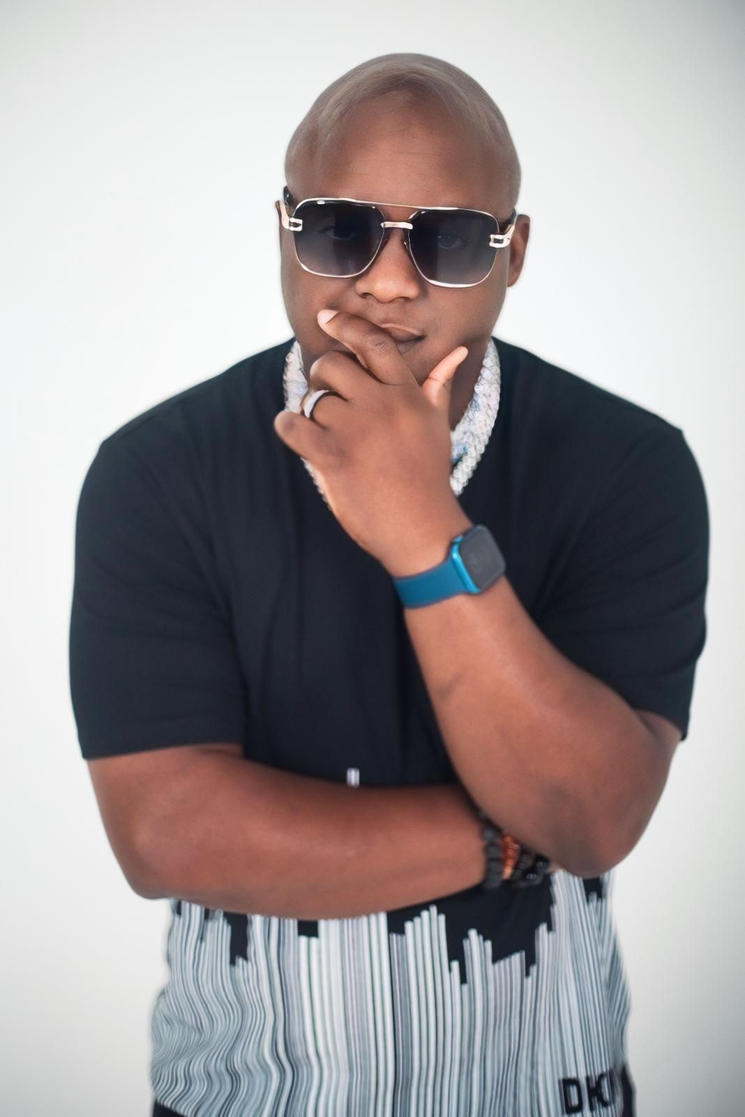 Man with crossed arms wearing a black t-shirt and blue digital watch.
